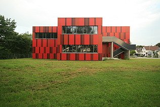 Photo of an exterior view of the Einhard School in Seligenstadt. You can see a red facade.
