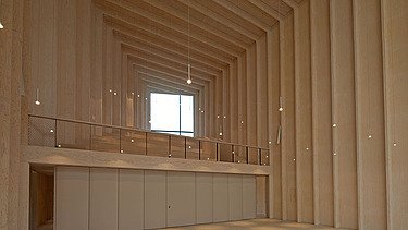 Foto des Innenraums der Immanuelkirche Köln. Man sieht einen leeren, hohen Raum mit Holzwänden und Holzdecke.