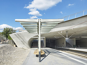 Foto von der Haltestelle Staatsgalerie in Stuttgart. Man sieht Zugschienen und Betonschalungen und einen  überdachten Wartebereich.