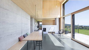 Foto eines modernen Holzhauses mit Holzfassade. Innenaufnahme Esszimmer. Holz- Glas- und Betonwände.