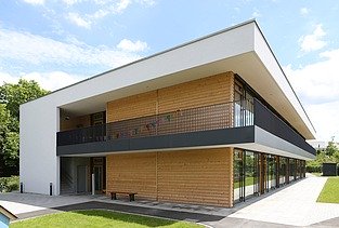 Außenaufnahme der Kita in Frankfurt. Man sieht ein Gebäude aus Holz mit Flachdach.