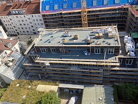 Foto des Rohbaus VINZENT in München. Zu sehen ist ein eingerüstetes, mehrgeschossiges Gebäude von oben.