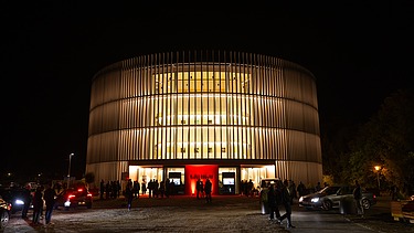 Nachtaufnahme des Globe Theaters in Coburg. Zu sehen ist ein rundes Gebäude aus Holz.