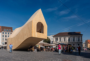 Foto des NEXT500-Pavillons auf dem Augsburger Marktplatz. Sie können ein modernes Holzgebäude sehen.
