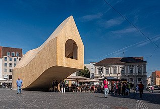 NEXT500 Pavillon, Augsburg Foto des NEXT500-Pavillons auf dem Augsburger Marktplatz. Sie können ein modernes Holzgebäude sehen.