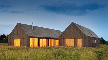 Foto eines modernen Holzhauses in U-Form mit Holzfassade. LENO-BSP.