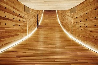 Foto eines beleuchteten, geschwungenen Innenraums aus Holz der Skulptur The Smile des Design Festivals in London.