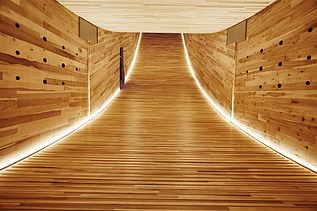 Photo of an illuminated, curved wooden interior of the sculpture The Smile at the Design Festival in London.