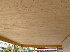 Foto eines Rohbaus aus Holz. Man sieht einen Innenraum mit Holzdecke