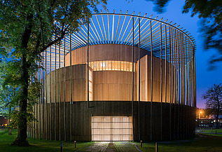 Foto des Elizabethan Theatres in Condette Frankreich. Zu sehen ist ein rundes Holzgebäude bei Nacht.