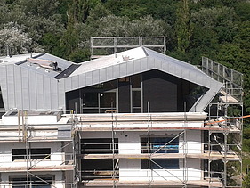 Foto eines Ausschnittes eines mehrgeschossigen Gebäudes. Man sieht eine Aufstockung aus Holz.