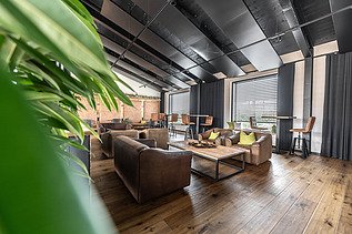 Photo of an interior of the Maisel brewery in Bayreuth. You can see a lounge with a wooden floor.