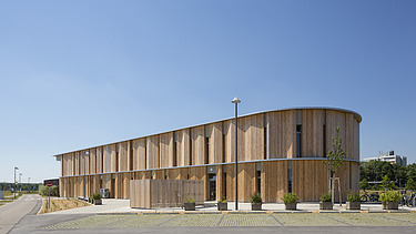 Außenaufnahme der Kindertagesstätte Campeon Infineon in Neubiberg. Man sieht ein Gebäude mit Holzfassade.