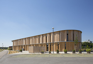 Außenaufnahme der Kindertagesstätte Campeon Infineon in Neubiberg. Man sieht ein Gebäude mit Holzfassade.