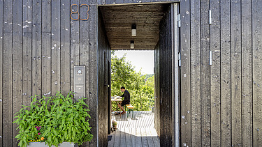 Foto eines Wohnhauses aus Holz. Detailbild der dunklen Holzfassade.