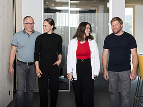 Photo of four people walking along an office corridor.