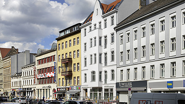 Photo of an exterior shot of several multi-storey buildings on a busy street.  The extension of the German Choir Center Berlin can be seen.