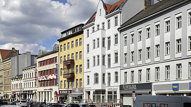 Photo of an exterior shot of several multi-storey buildings on a busy street.  The extension of the German Choir Center Berlin can be seen.