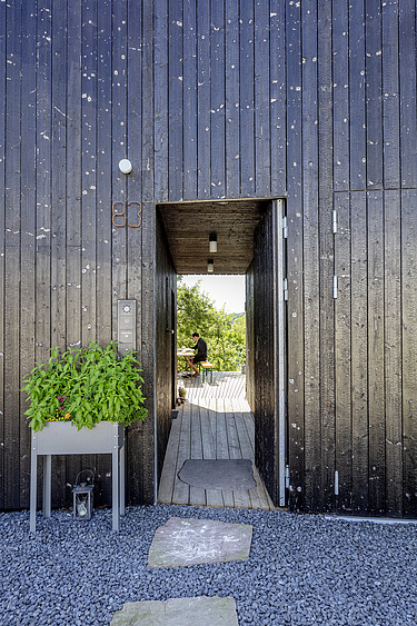 Foto eines Wohnhauses aus Holz. Detailbild der dunklen Holzfassade.