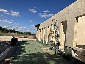 Baustellenfoto, auf dem die Montage der ersten Brettsperrholzelemente zu sehen ist.