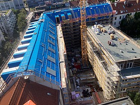 Foto des Rohbaus VINZENT in München. Zu sehen ist ein eingerüstetes, mehrgeschossiges Gebäude von oben.