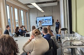 Aktuelles ZÜBLIN Timber Foto eines Seminarraumes bei ZÜBLIN Timber mit Personen die auf einen großen Bildschirm schauen