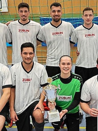 Teamfoto einer Hobby-Fußballmannschaft in einer Sporthalle.