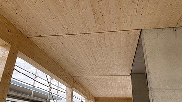 Photo of a wooden building shell. You can see an interior with a wooden ceiling.