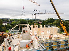 Photo of Witten University from the outside. You can see the assembly of large wooden elements.