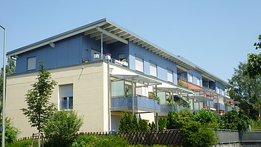 Foto eines mehrgeschossigen Gebäudes mit weiß-blauer Fassade.