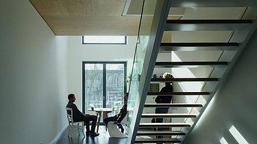 Photo of an interior with staircase. People are sitting and standing at the window.