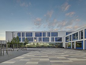 Exterior view of the Gymnasium München-Nord. You can see a large, white building with a flat roof.