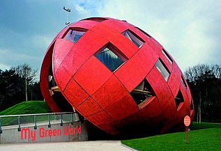 Regierungspavillion Floriade NL-VENLO Foto eines rießigen, schrägliegenden Holzeis mit orangefarbiger Holzfassade und Fenstern.