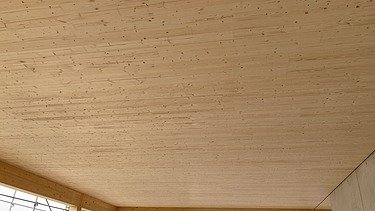 Photo of a wooden building shell. You can see an interior with a wooden ceiling