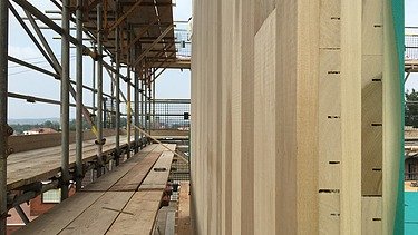 Photo of a LENO cross-laminated timber wall. Side cross-section. Assembly photo with scaffolding.