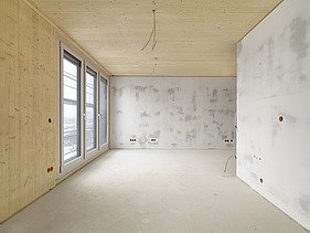 Photo of the SKAIO Stadtsiedlung building in Heilbronn. You can see an interior with wooden surfaces and concrete walls.