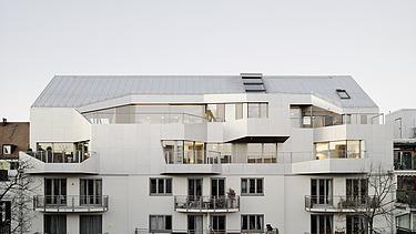 Photo of an exterior shot of a multi-storey building with a wooden extension. The building has a white façade.