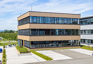 Foto eines Holzgebäudes mit Holz-Glasfassade und Flachdach.