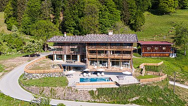 Photo of a wooden hotel in the middle of the mountain landscape.