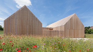 Foto eines modernen Holzhauses in U-Form mit Holzfassade. LENO-BSP.