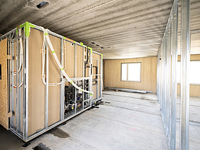 Photo of a building shell. You can see wooden walls and a bathroom module
