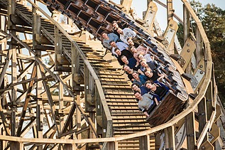Foto der Holzachterbahn Colossos im Heide Park Resort Soltau. Zu sehen ist ein Teil der Achterbahn und ein Wagon mit Menschen.