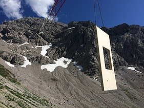 Foto der Holzbaumontage des Waltenberger Haus in Oberstdorf. Helikopter-Montage eines schwebenden LENO-BSP-Elements.