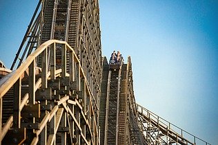 Foto der Holzachterbahn Colossos im Heide Park Resort Soltau. Zu sehen ist ein Teil der Achterbahn und ein Wagon mit Menschen.