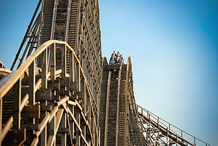 Photo of the Colossos wooden roller coaster at Heide Park Resort Soltau. You can see a part of the roller coaster and a wagon with people.