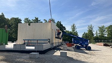 Construction site photo showing the assembly of the first cross-laminated timber elements.