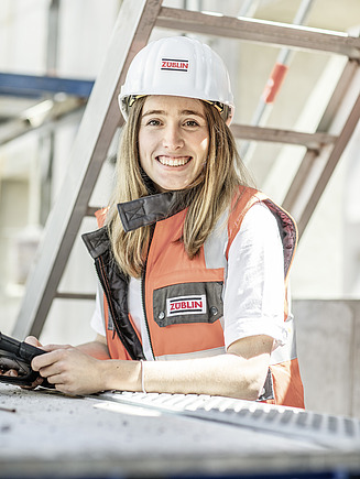 Foto von einer jungen Frau mit Helm und in Baustellenkleidung auf einer ZÜBLIN-Baustelle