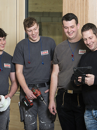 Photo of four carpenters standing in production looking into a tray.