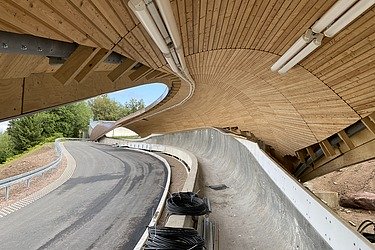 Photo of a luge track. You can see a wooden roof construction.