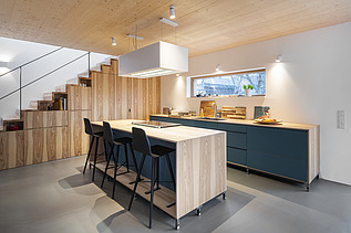 Foto eines Küchenwohnraumes mit sichtbarer LENO-Brettsperrholzdecke.